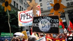 FILE - Climate change activists carry signs as they march during a protest in Philadelphia a day before the start of the Democratic National Convention, July 24, 2016.