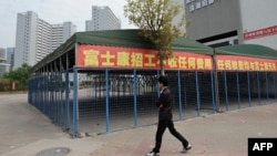 This picture taken on February 22, 2013 shows a man walking past empty tents in a Foxconn recruitment center in Shenzhen, south China's Guangdong province. 