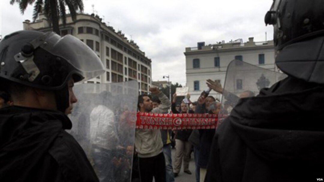 Demonstran berhadap-hadapan dengan polisi anti-huru-hara di Tunis, Tunisia.