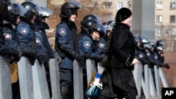 A woman walks past as Ukrainian riot police stand at the entrance of the regional administrative building in Donetsk, Ukraine, March 7, 2014.