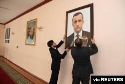 Afghan embassy staff hang a portrait of Afghan First Vice President Amrullah Saleh, who declared himself the "legitimate caretaker president", on the wall at the embassy in Dushanbe, Tajikistan, in this picture released August 18, 2021.