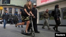 A women rides a scooter along 42nd Street in New York.