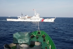 FILE - A ship of the Chinese Coast Guard (top) is seen near a vessel of the Vietnam Marine Guard, in the South China Sea, about 210 km (130 miles) off the shore of Vietnam, May 14, 2014.