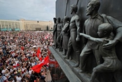 In this Tuesday, Aug. 18, 2020 file photo Belarusian opposition supporters gather for a protest rally in front of the government building at Independent Square in Minsk, Belarus, with a Soviet era sculptures in the foreground.