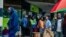 Residents walk in a street as others queue outside a bank in Harare, Nov. 15, 2017.