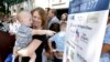 Jennifer Wonnacott holds her son Gavin as he points to a sign showing support of a measure requiring nearly all California school children to be vaccinated, at a news conference after the bill was signed by Gov. Jerry Brown, June 30, 2015, in Sacramento, California.