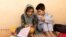 Samira (9) dan Aminullah saling membantu dalam mengerjakan PR di panti asuhan di Kabul, Afghanistan, 10 Oktober 2021. (REUTERS/Jorge Silva)