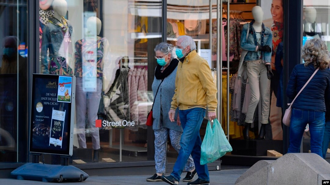 Para pejalan kaki mengenakan masker wajah berjalan melintas sebuah toko di tengah wabah virus corona, di Leipzig, Jerman Timur, 20 April 2020. (Foto: AFP)