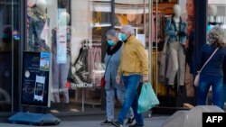 A woman and a man wearing face masks walk past a shop in Leipzig, eastern Germany