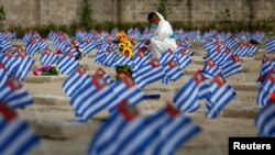 A cemetery worker puts flowers on the graves of people who died of the coronavirus disease during The Day of the Dead celebration, as the outbreak continues, at La Bermeja cemetery in San Salvador, El Salvador, Nov. 2, 2020.