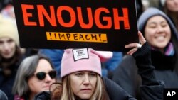 FILE - A woman holds a sign expressing her opinion about impeaching President Donald Trump at a rally organized by Women's March NYC at Foley Square in Lower Manhattan in New York, , Jan. 19, 2019. 