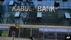 An Afghan girl walks past by Kabul Bank's main office in Kabul, Afghanistan, March 27, 2011.