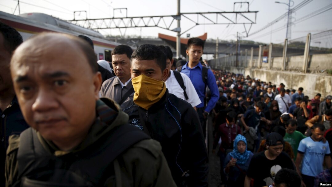 FILE - Indonesia workers walk through train tracks as they go to work at Tanah Abang train station in Jakarta, Oct. 15, 2015. An Indonesian presidential decree requires all employers to provide language training in Bahasa Indonesia to foreign workers. 