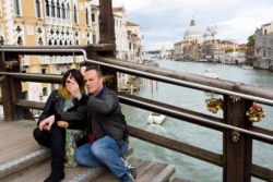 FILE - A couple takes its picture on the Ponte dell'Accademia (Academia bridge) spanning the Grand Canal in Venice, northern Italy.