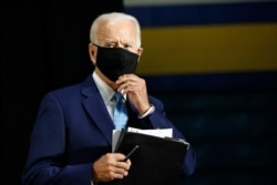 FILE - Democratic presidential candidate former Vice President Joe Biden puts on a face mask as he departs after speaking at Alexis Dupont High School in Wilmington, Delaware, June 30, 2020.