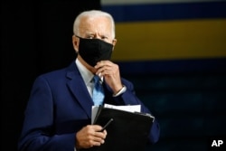 Democratic presidential candidate, former Vice President Joe Biden puts on a face mask as he departs after speaking at Alexis Dupont High School in Wilmington, Del., June 30, 2020.