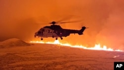 This image made from video provided by the Icelandic Coast Guard shows its helicopter flying near magma running on a hill near Grindavik on Iceland's Reykjanes Peninsula late Dec. 18, or early Dec. 19, 2023.