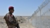 FILE- A Pakistani army soldier stands guard along with border fence at the Pakistan-Afghanistan border near the Punjpai area of Quetta in Balochistan on May 8, 2018.