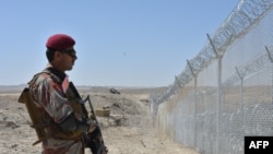 FILE- A Pakistani army soldier stands guard along with border fence at the Pakistan-Afghanistan border near the Punjpai area of Quetta in Balochistan on May 8, 2018.