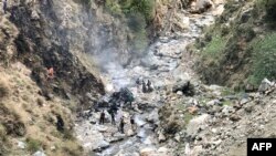 Petugas keamanan memeriksa puing-puing kendaraan yang membawa warga negara China yang jatuh ke jurang di pegunungan Jalan Raya Karakoram akibat serangan bunuh diri di dekat kota Besham di distrik Shangla, provinsi Khyber Pakhtunkhwa, 26 Maret 2024. (AFP)