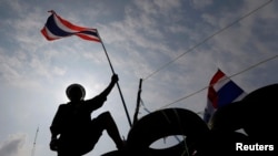 Seorang demonstran anti-pemerintah mengibarkan bendera di atas barikade di dekat kantor pemerintah di Bangkok (18/2). (Reuters/Damir Sagolj)