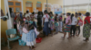 Women wait outside the family clinic. Jhpiego, a non-profit health organization, has folded screening into HIV-related health services, Boane, Mozambique, Nov. 20, 2014. (Gillian Parker/VOA)