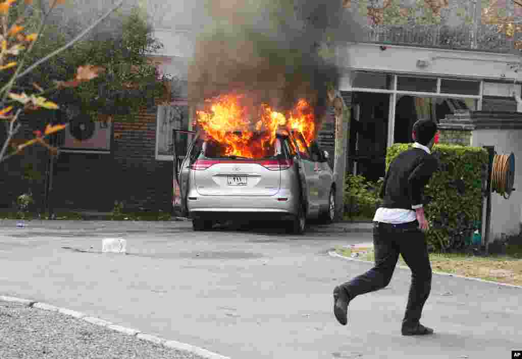 An Iranian hard-line protester runs inside the British Embassy as a diplomatic vehicle is set on fire by demonstrators. (AP Photo/Vahid Salemi)