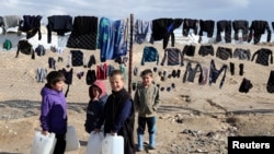 Sejumlah anak-anak membawa tangki air di kamp pengungsi al-Hol di Suriah, pada 8 Januari 2020. (Foto: Reuters/Goran Tomasevic)