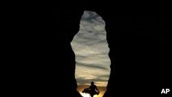 A woman is seen against the setting sun in Monument Rocks, May 20, 2020, south of Oakley, Kansas.