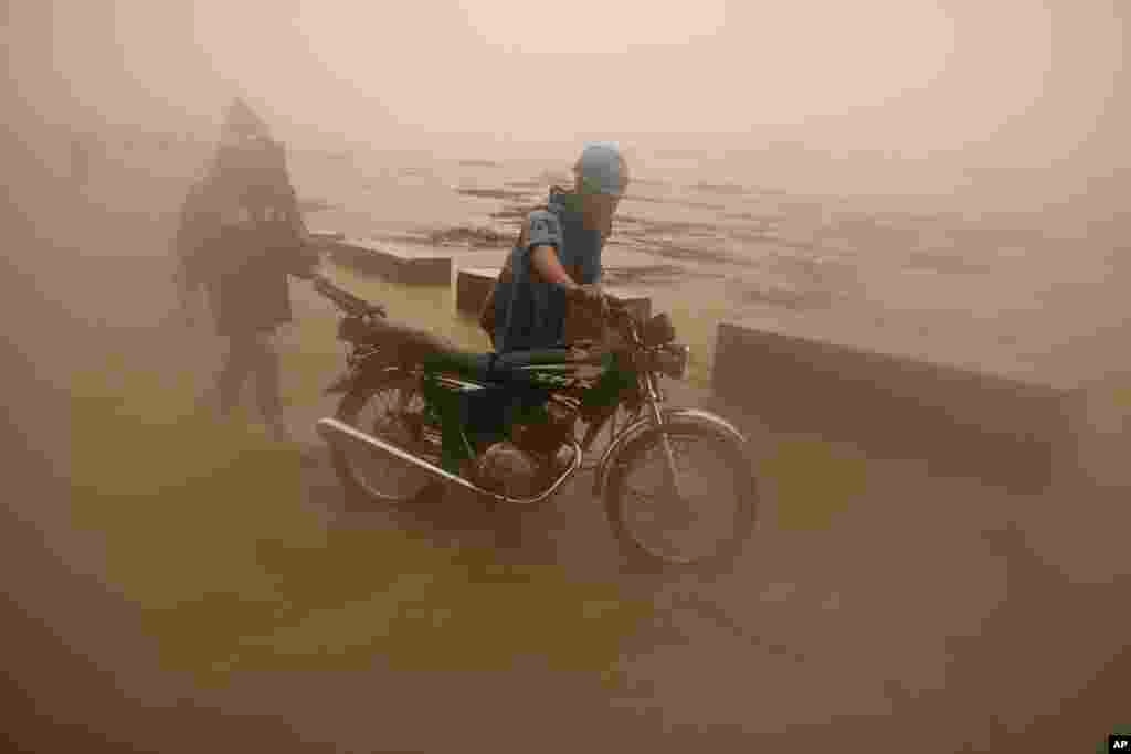 A resident pushes his motorcycle along floods from a swollen river caused by heavy rains from Typhoon Toraji in Ilagan City, Isabela province, northern Philippines.