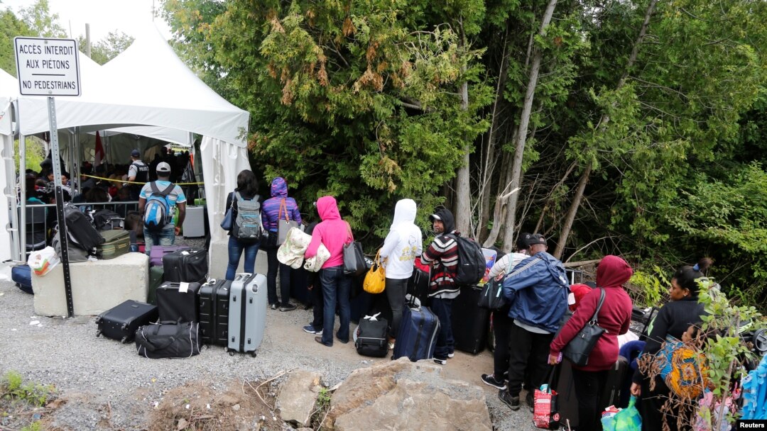 A line of asylum seekers who said they were from Haiti wait to enter into Canada from Roxham Road in Champlain, New York, Aug. 7, 2017.