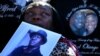 FILE - A woman holds a picture of Alfred Olango as she listens to speeches during an Oct. 1, 2016, rally and march to protest the fatal police shooting of the Ugandan immigrant in El Cajon, California, four days earlier.