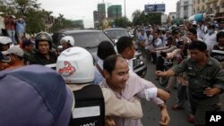 A Cambodian government supporter, center, tries to block the convoy of Cambodia National Rescue Party (CNRP) lawmakers near Royal Palace where party lawmakers deliver a petition to the King Norodom Sihamoni in Phnom Penh, Cambodia, Monday, May 30, 2016. 