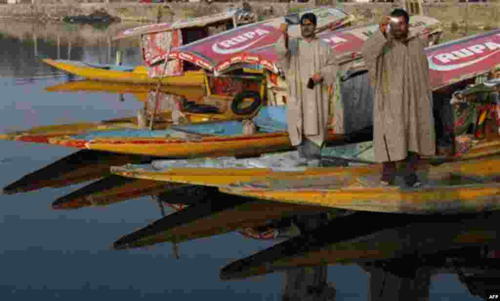 Kashmiri boatmen watch partial solar eclipse through a black film, at the Dal lake in Srinagar, India, Tuesday, Jan. 4, 2011. People in parts of north India viewed a partial eclipse Tuesday as the moon crossed the sun's path. (AP Photo/Mukhtar Khan)