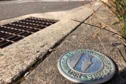 A Green Streets Managing Stormwater emblem is displayed by a stormwater drain near the Immigration and Customs Enforcement building where recent protests have been held in Portland, Ore., on Oct. 2, 2020.