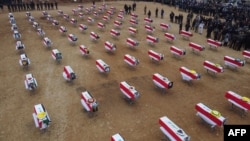 An aerial picture shows mourners gathering around coffins wrapped with the Iraqi flag during a mass funeral for Yazidi victims of the Islamic State (IS) group in the northern Iraqi village of Kojo in Sinjar district. (File)