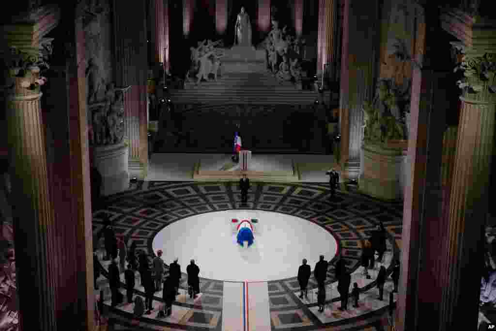 French President Emmanuel Macron stands by the coffin of World War I fighter Maurice Genevoix inside the Pantheon monument in Paris.