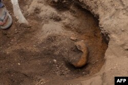 FILE - A human skull can be seen in a mass grave with victims of the 1994 Rwandan Genocide found under the foundations of a house in Ngoma, Rwanda on January 23, 2023.