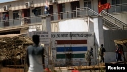 FILE: Men carry fishing ropes outside the gates of the Chinese-owned Golden Lead fishmeal factory in the fishing village of Gunjur, Gambia, April 17, 2018.