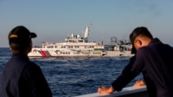 Dua anggota Penjaga Pantai Filipina bersiaga saat kapal Penjaga Pantai China menghalangi kapal mereka mengirim pasokan ulang di Second Thomas Shoal di Laut China Selatan (foto: dok). 