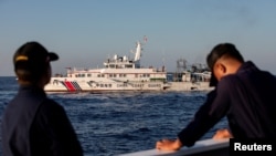 Dua anggota Penjaga Pantai Filipina bersiaga saat kapal Penjaga Pantai China menghalangi kapal mereka mengirim pasokan ulang di Second Thomas Shoal di Laut China Selatan (foto: dok). 