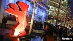 People walk next to the logo for the upcoming 66th Berlinale International Film Festival in Berlin, Feb. 9, 2016.