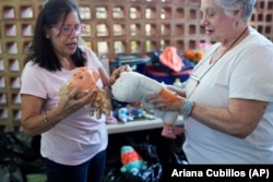 Volunteers Aides Jimenez, left, and Miriam Goodman, discuss the best way to restore a recycled doll at the non-profit foundation Hospital de los Peluches, or Hospital of Stuffed Animals, in Caracas, Venezuela, Thursday, Dec. 5, 2024. (AP Photo/Ariana Cubillos)