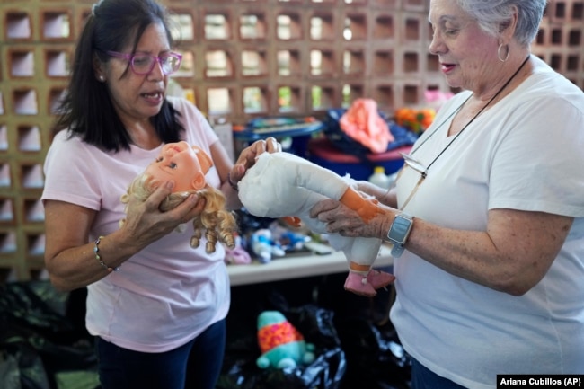 Volunteers Aides Jimenez, left, and Miriam Goodman, discuss the best way to restore a recycled doll at the non-profit foundation Hospital de los Peluches, or Hospital of Stuffed Animals, in Caracas, Venezuela, Thursday, Dec. 5, 2024. (AP Photo/Ariana Cubillos)