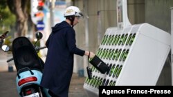 FILE - A man swaps batteries at a Gogoro GoStation unit in Taipei on March 26, 2018.