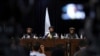 In front of a Taliban flag, Taliban spokesman Zabihullah Mujahid, center, speaks at his first news conference, in Kabul, Afghanistan, Aug. 17, 2021. 