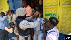 Bystanders are assisted after police fired tear gas to disperse a protest demanding justice for a student demonstrator who was gunned down by police the previous week in Port-au-Prince, Haiti, Oct. 5, 2020. 