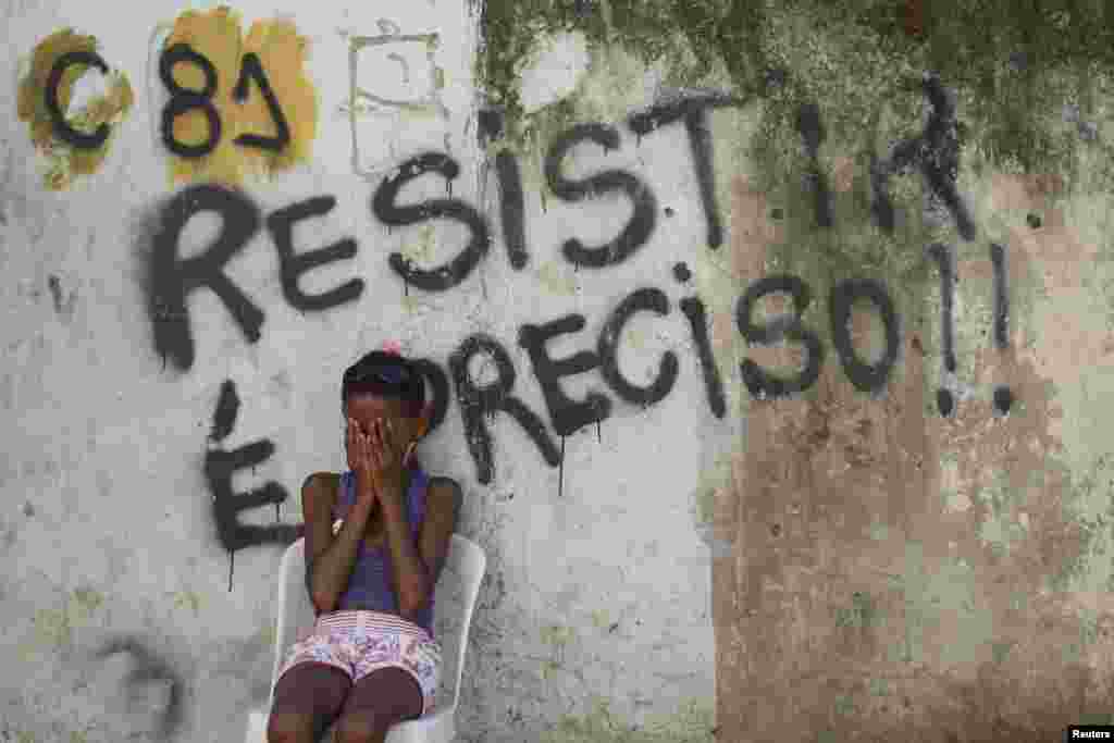 A girl sits in front of a wall with graffiti that reads, &quot;We must resist,&quot; in Metro slum near Maracana stadium in Rio de Janeiro. Residents are protesting eviction from their homes. The removal of the community is part of the renovation works of the area for the 2014 World Cup. 