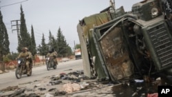 Syrian opposition fighters drive past a damaged government vehicle south of Hama, Syria, Dec. 7, 2024.