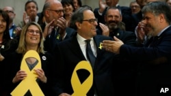 Newly appointed Catalan president Quim Torra, center, holds a yellow ribbon in support of Catalonian politicians who have been jailed on charges of sedition, at the end of a parliamentary vote session in Barcelona, Spain, May 14, 2018. 